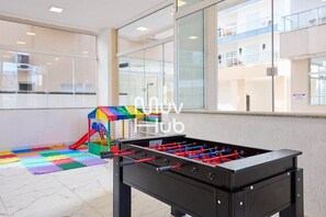 Ein Kicker und ein bunter Spielbereich in der Hotelhalle mit großen Fenstern und Blick ins Innere des Gebäudes.