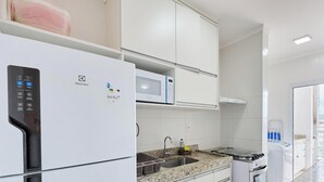 A modern kitchen with a built-in microwave, a stainless steel sink, and a gas stove. - Residencial Saint Barth (Ubatuba)