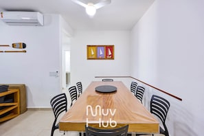 A dining area with a wooden table, black chairs, and a ceiling fan. There is a painting of sailboats on the wall. - Residencial Saint Barth (Ubatuba)