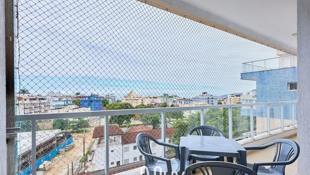 A balcony with a view of a cityscape and the sea. There are two tables and four chairs. - Residencial Saint Barth (Ubatuba)