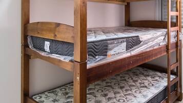 Een stapelbed met drie niveaus, houten frame en matrassen met een dessin.
