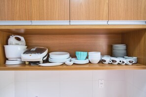 Una repisa de cocina con vajilla blanca y azul, una cafetera y una pila de platos.