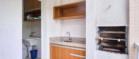 A compact kitchen with a sink, wooden cabinets, and a built-in oven.