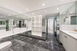 A modern bathroom with a large mirror, a bathtub, and a toilet. - The Knightsbridge Residences (London)