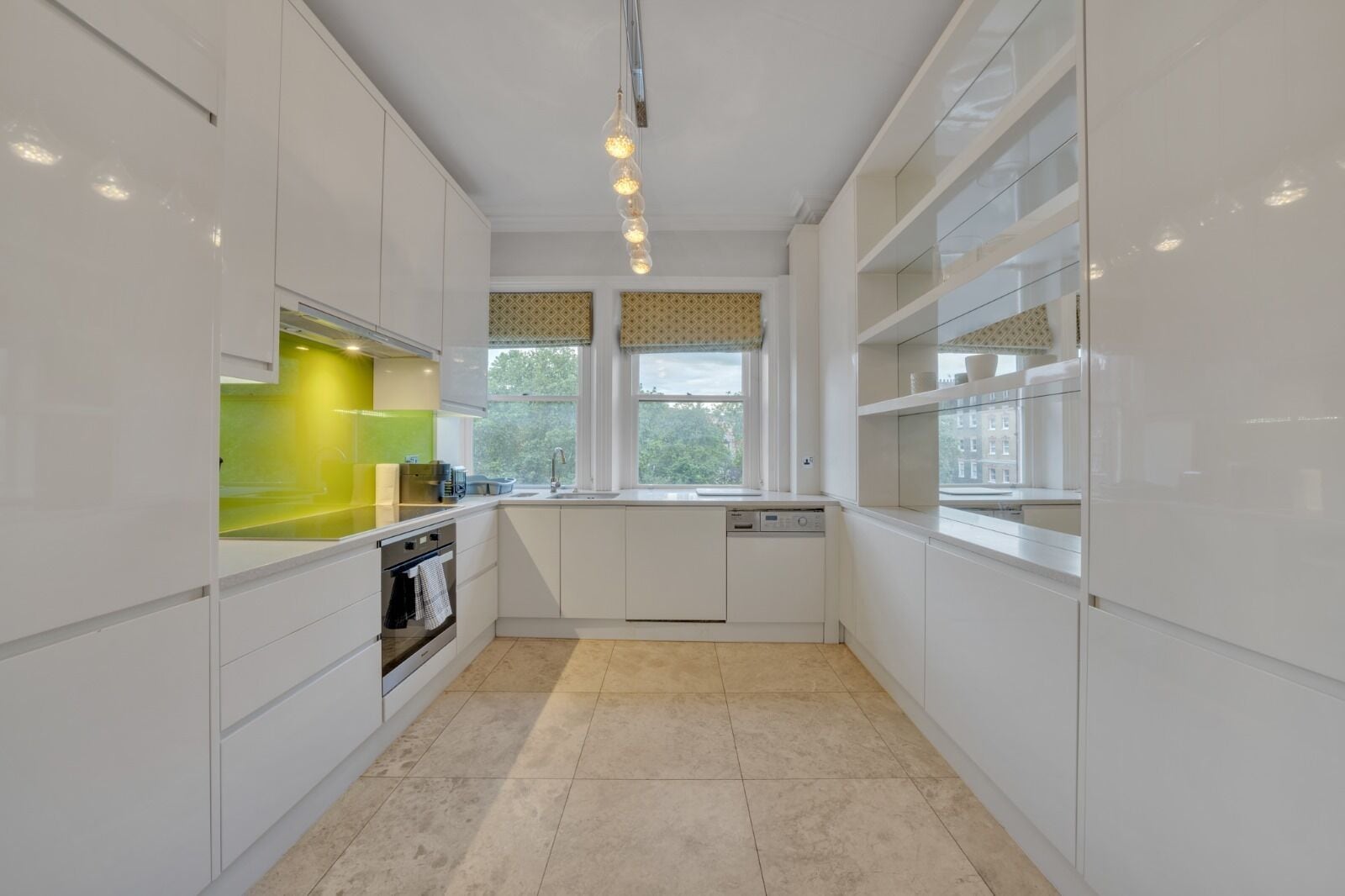 A modern kitchen with white cabinets, a green countertop, and a window with a view of trees.