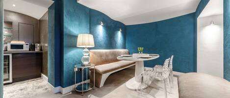 Uma sala de estar moderna com uma parede azul decorativa, uma mesa de jantar redonda com cadeiras, um sofá e uma luminária.