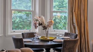 A dining table set with plates, glasses, and a vase of flowers. - The Knightsbridge Residences (London)