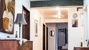 A hallway with a wooden dresser, a lamp, and a mirror on the left. There is a staircase in the background leading to another room. - HOTEL SOLACHE INN (Zitácuaro)