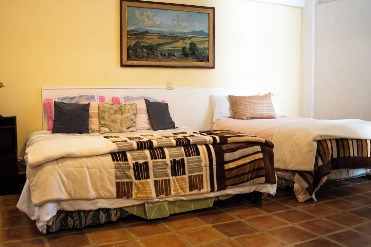 Una cama doble con colcha, una mesita de noche y un cuadro en la pared.