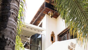 A multi-level building with balconies, a palm tree, and a stone wall. - HOTEL SOLACHE INN (Zitácuaro)