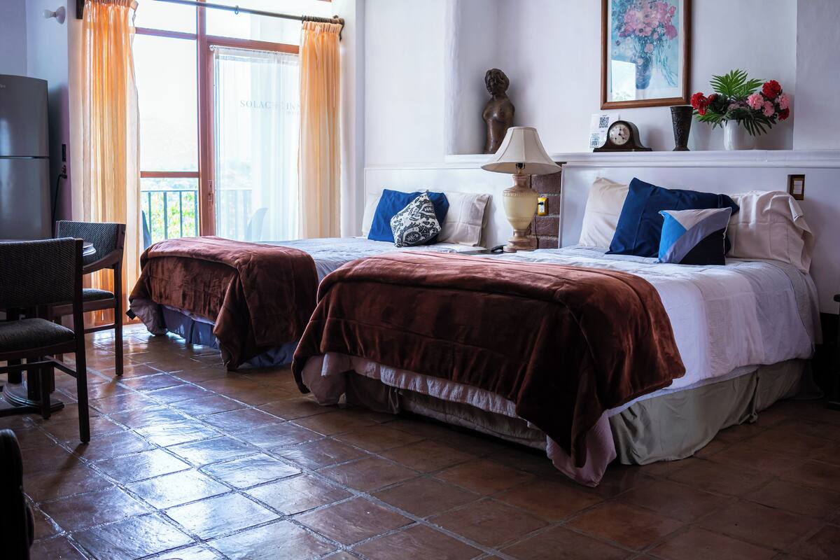 Habitación de hotel con dos camas, un escritorio y una silla.
