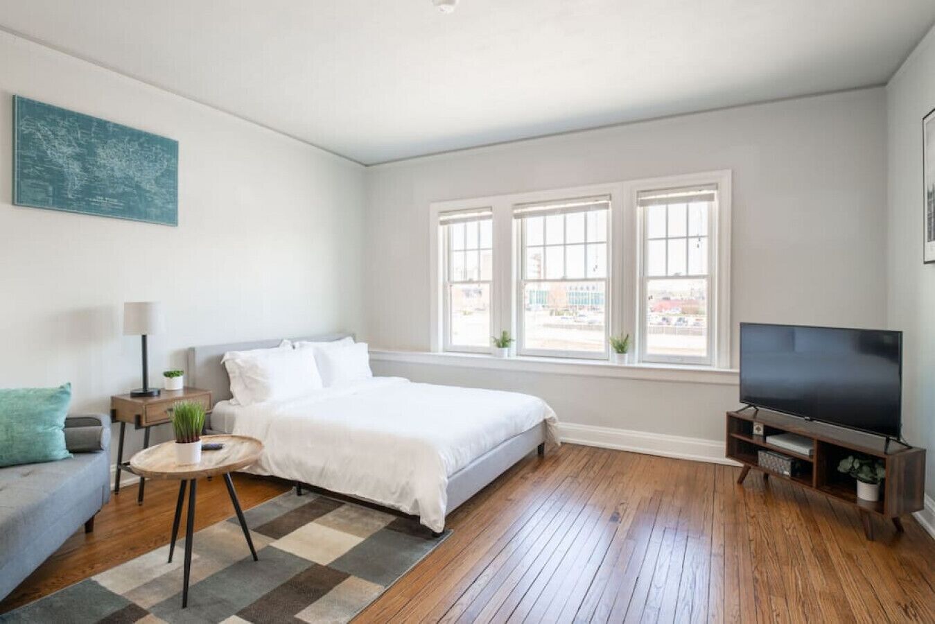 Un dormitorio moderno con cama, televisor, sofá y ventana con vistas.