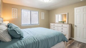 A bedroom with a bed, dresser, and two windows with blinds. - WOOD`INN - Cozy 2BD over the bridge (East Peoria)