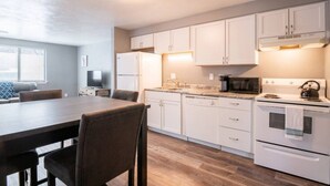 A modern kitchen with white cabinets, a dining table, and a kitchen island. - WOOD`INN - Cozy 2BD over the bridge (East Peoria)