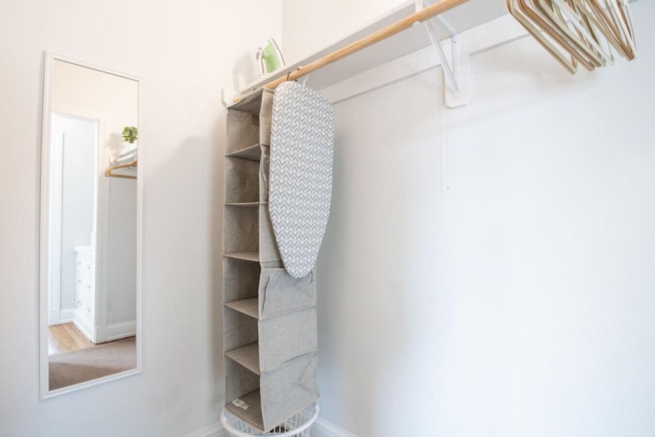 A corner of a room with a built-in shelving unit, a mirror, and a hanging rack.