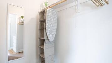 A corner of a room with a built-in shelving unit, a mirror, and a hanging rack.