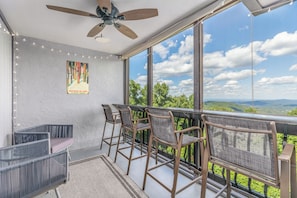 A balcony with chairs and a ceiling fan, large windows with a view of the landscape. - Huge Family Retreat - Epic Mountain Views - 3 Suites + Pool (Gatlinburg)