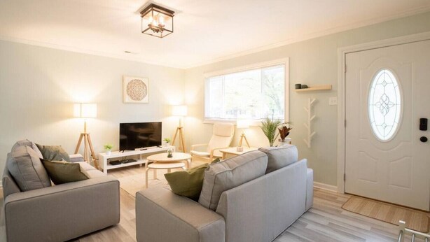 Un salon moderne avec un canapé, un téléviseur et une lampe.