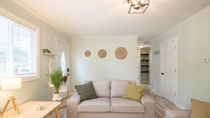Un salon avec un canapé beige, une petite table et une lampe. On y trouve trois décorations murales de forme circulaire et une plante posée sur une étagère.