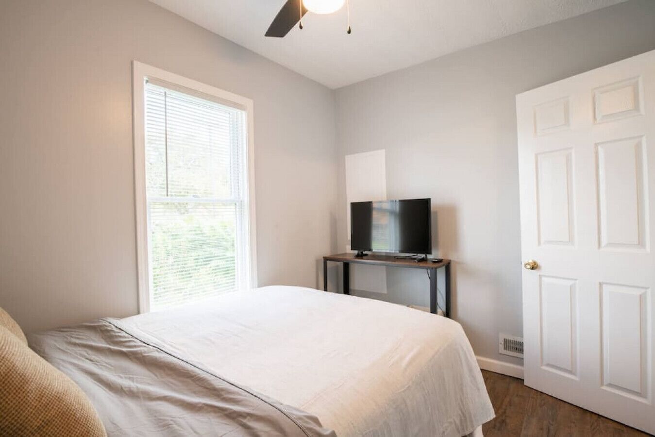 A bedroom with a bed, a television on a small table, and a door.