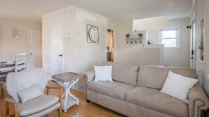 Ein Wohnzimmer mit einem beigen Sofa, zwei Sesseln, einem kleinen Holztisch und einer weißen Tür.