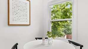 A white dining table with a glass vase and a framed artwork on the wall. - Halcyon Haven - A Heavenly Homestead for 4 (Morton)