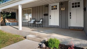 A covered porch with two doors, a bench, and two chairs. - Halcyon Haven - A Heavenly Homestead for 4 (Morton)