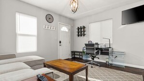 A modern living room with a sofa, a wooden coffee table, and a TV mounted on the wall.