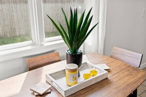 A dining table with a potted plant, a jar of honey, and lemon slices.