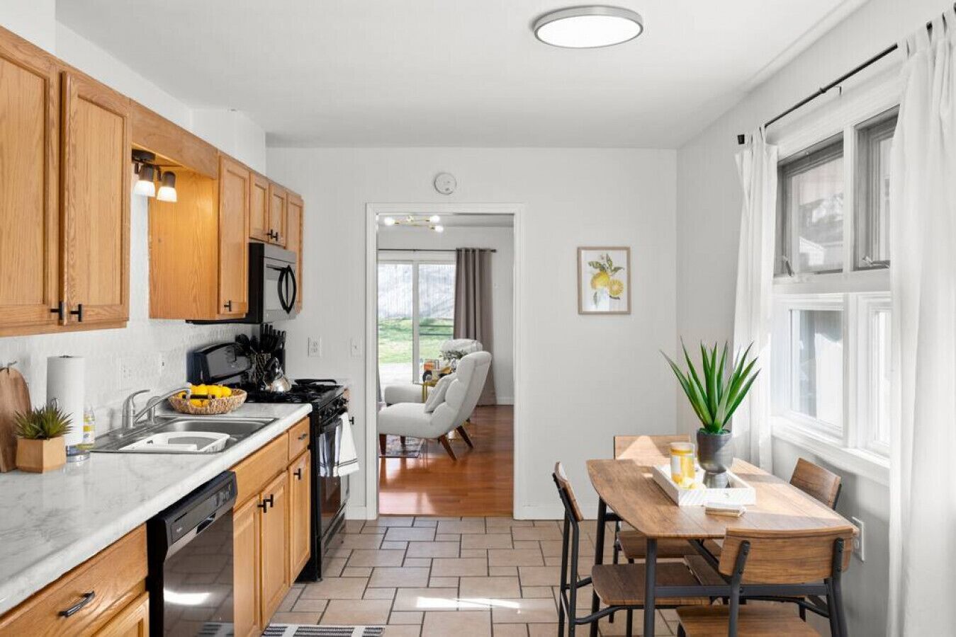 Una cocina moderna con armarios de madera, un comedor con mesa y sillas, y vistas al exterior a través de una puerta de cristal.