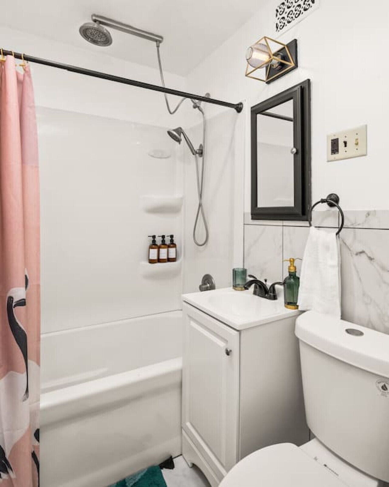 Een badkamer met een bad, toilet en wastafel. Er is een douche boven het bad en een handdoekrek is zichtbaar.