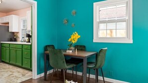 A dining area with teal walls, a wooden table, and green chairs. - Art Deco Oasis: A Stylish Retreat (Peoria Heights)