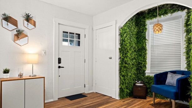Een modern interieur met een houten vloer, witte muren, een blauwe fauteuil en een verticale groene wandtuin.