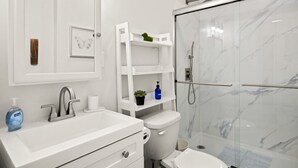 Een moderne badkamer met een witte wastafel, een toilet en een douchecabine met glazen wanden.