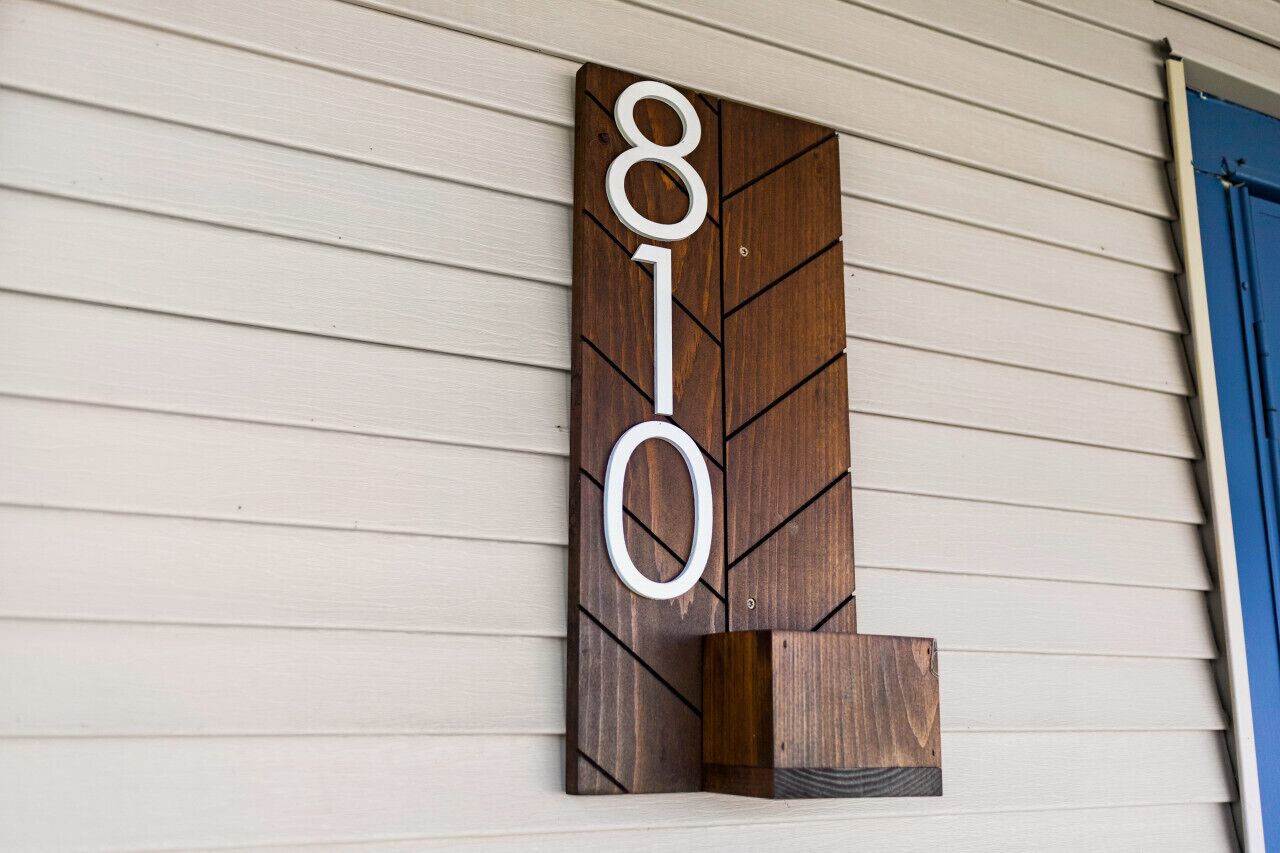 Un letrero de número de casa de madera con los dígitos 810 montado en una pared.