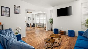 Een moderne woonkamer met een blauwe bank, een salontafel en een tv aan de muur.