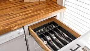 A kitchen with a wooden countertop and a drawer containing utensils.