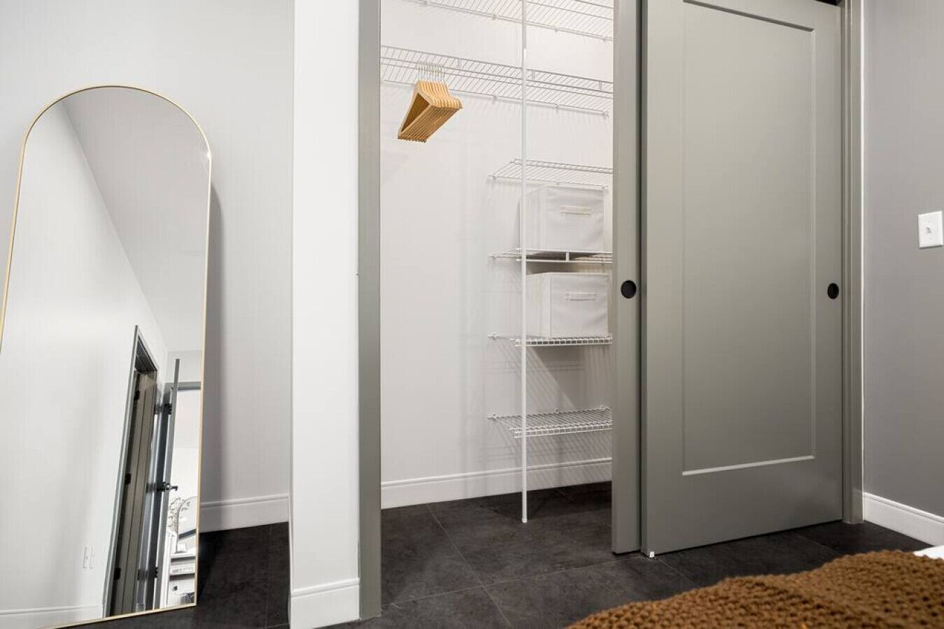 A hallway with a white door, a white shelving unit, and a brown rug.