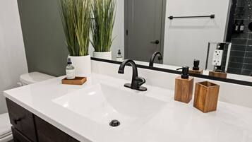 A bathroom with a white sink, black faucet, and wooden containers on the countertop.