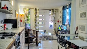 A kitchen with a gas stove, a refrigerator, and a microwave. There is a dining area with a glass table and chairs.