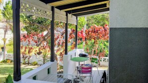 A covered outdoor area with a table and chairs, a pergola structure, and a garden with various plants and trees.