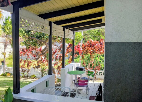 A covered outdoor area with a table and chairs, a pergola structure, and a garden with various plants and trees.