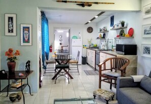A modern kitchen with white cabinets, a microwave, and a dining area with a table and chairs.