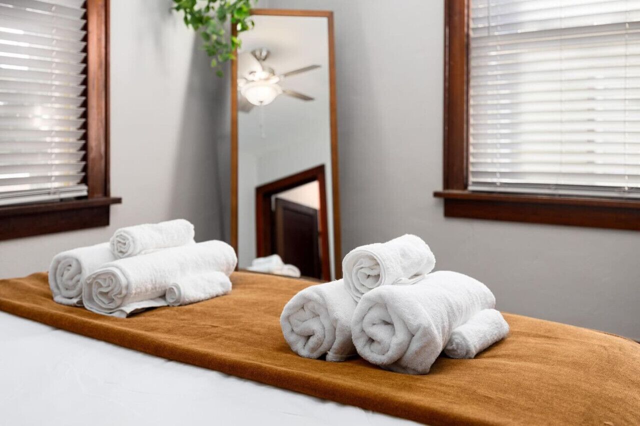 A bathroom with a wooden bench, towels, a mirror, and a ceiling fan.