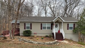 A single-story house with a front porch, a small garden, and a wooden deck. - Cozy house in quiet SML community. Close to State Park, wineries, Bridgewater. (Moneta)
