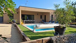 Un espace piscine extérieur moderne, doté d’un barbecue, de chaises longues et d ’une table à manger.