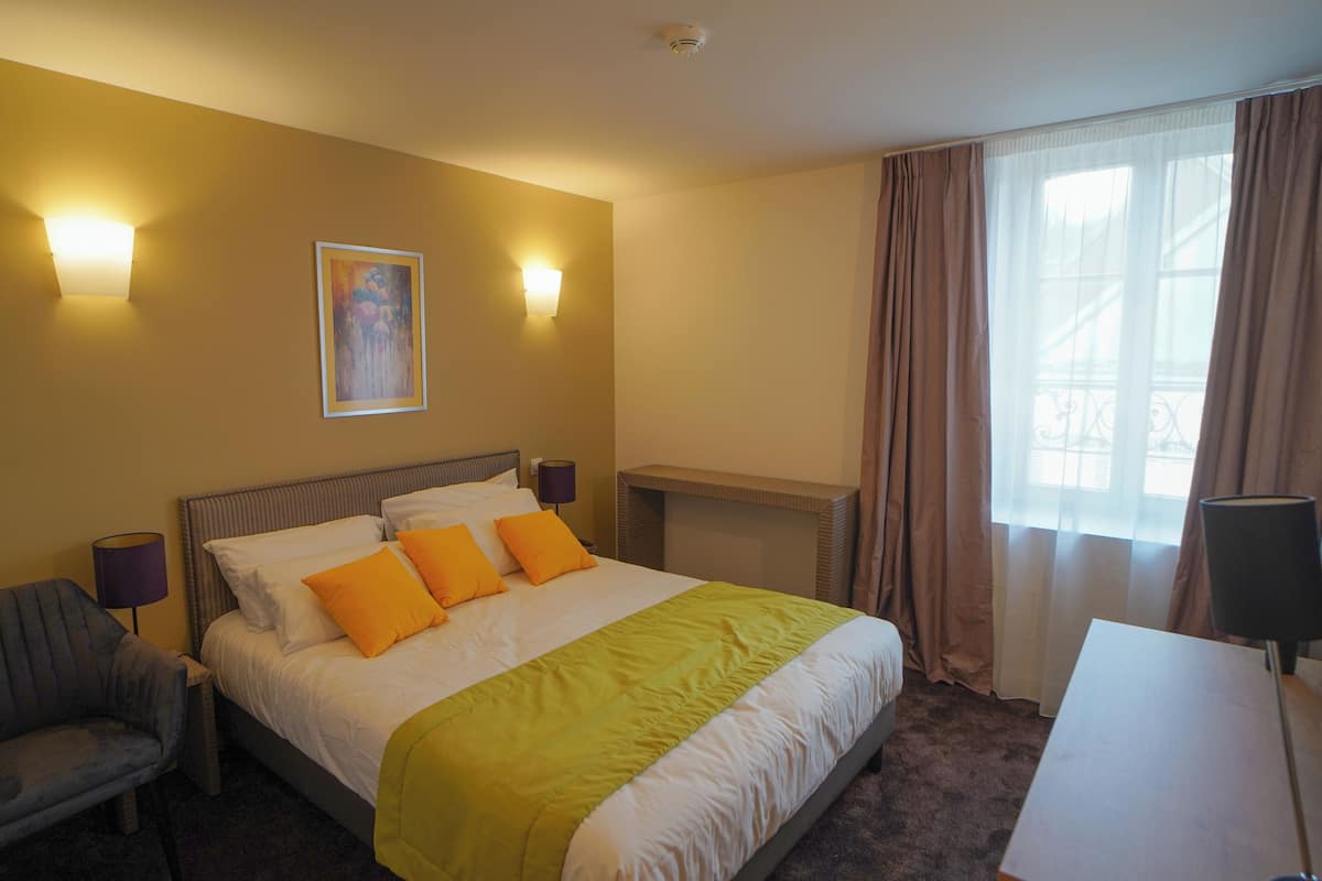 Une chambre d’hôtel avec un lit, une chaise, un bureau et une cheminée.