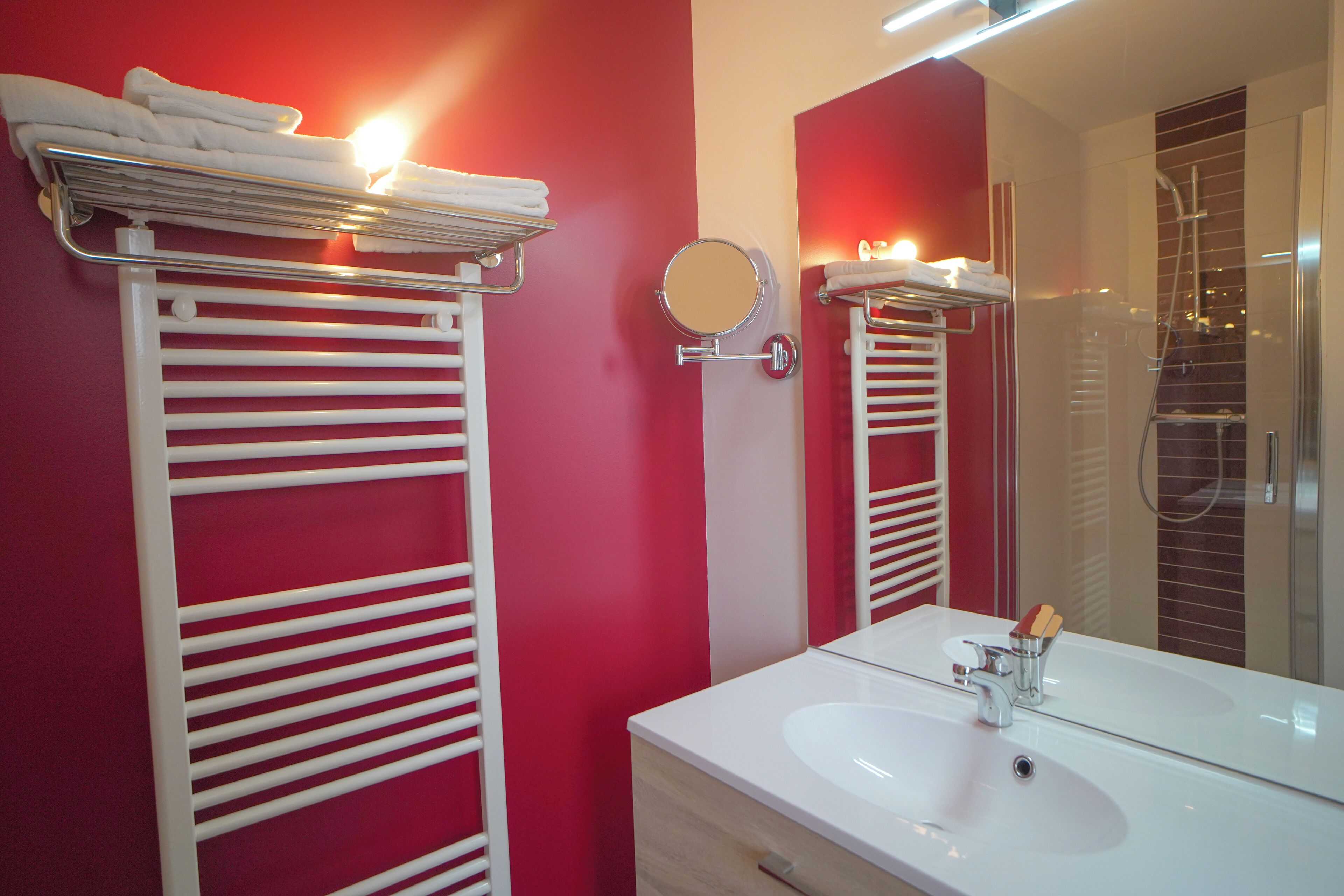 A modern bathroom with white towel racks, a large mirror, and a white sink.