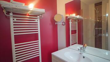 A modern bathroom with white towel racks, a large mirror, and a white sink.