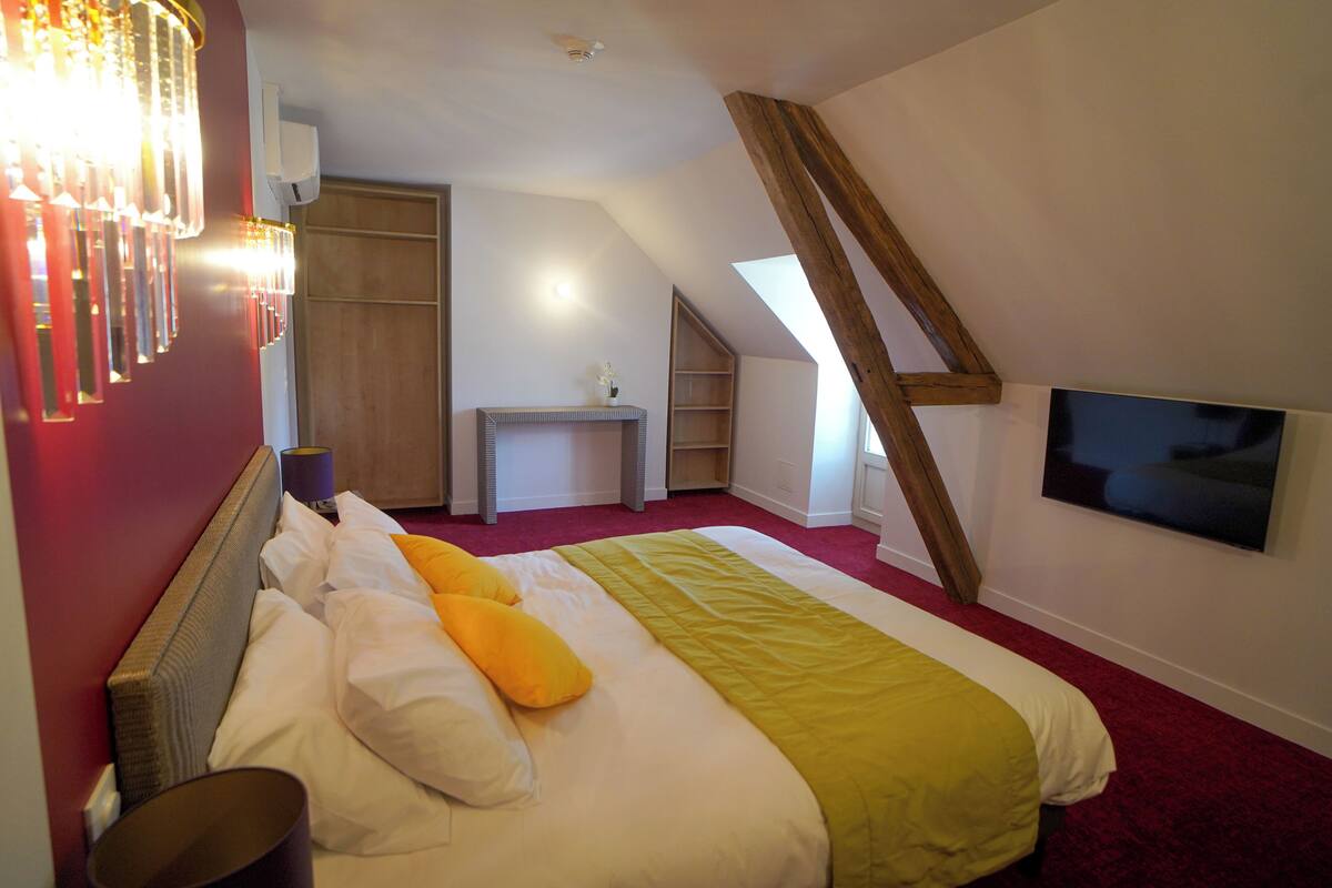 Une chambre à coucher avec un lit, un téléviseur fixé au mur et une lucarne.
